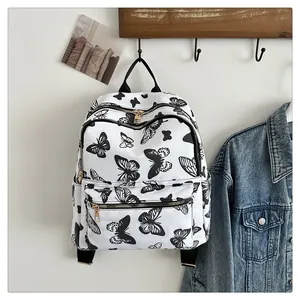 Close-up of white backpack with black butterfly prints and gold metal dual zippers