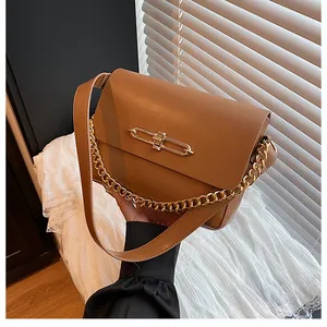Detail of caramel leather handbag featuring gold buckle and dual strap textures