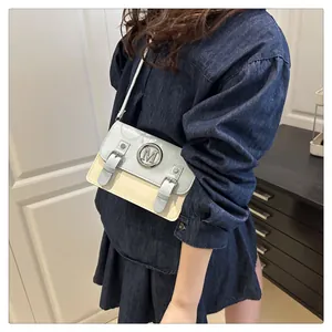 Detail shot of stylish color-block crossbody bag with metal M hardware and double buckle straps.