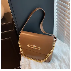 Detailed shot of a caramel brown matte leather handbag with gold metal clasp and chain strap