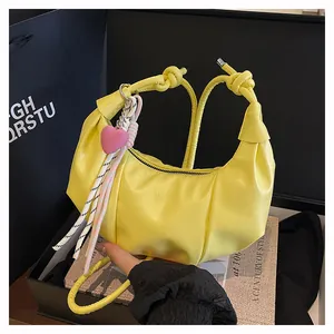 Macro detail of yellow croissant bag with fashion embossed text and pink heart charm