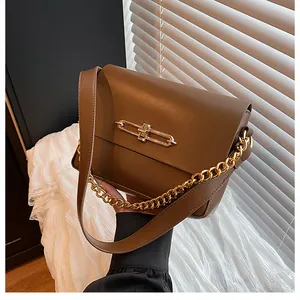 Detail view of brown matte leather bag featuring elegant gold clasp and chunky chain strap