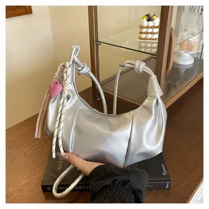 Close-up of silver crescent bag with knotted handle and pink heart charm detail