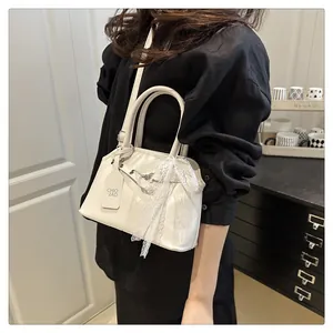 Dettaglio di una borsa a tracolla bianco crema con fiocco in pizzo e tracolla sottile