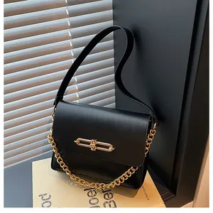 Detail view of black leather flap bag with chunky gold chain and metal bar lock