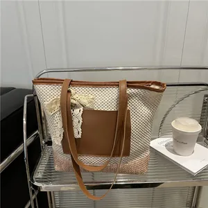 Large beige woven straw tote bag with brown leather pocket and lace bow detail for beach