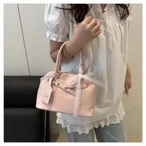 Dettaglio della borsa in pelle rosa con fiocco in pizzo bianco e fibbia metallica