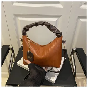 Close-up of caramel brown ruched handbag with vintage pleats and fashion tags