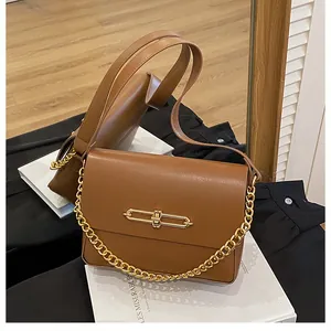 Detailed view of caramel leather handbag featuring golden bar lock and thick chain strap