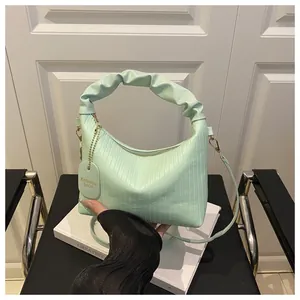 Detail of mint green pleated PU leather handbag with ruffled handle and gold hardware
