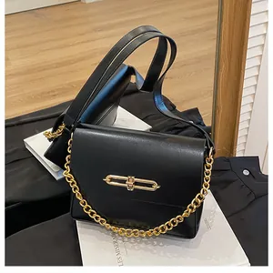 Detail of minimalist black crossbody bag with gold chain strap and metallic oval lock