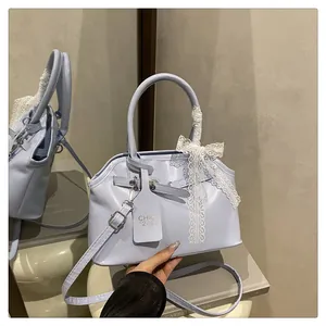 Dettaglio borsa a mano lilla in pelle con fiocco in pizzo bianco e doppi manici corti