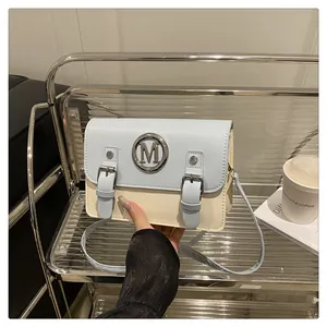 Stylish color-block crossbody bag with metal M logo and buckle straps for women daily use.