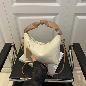 Chic pleated crossbody bag in creamy white with stylish brown twisted top handle