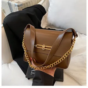 Close-up of brown faux leather handbag with a gold geometric clasp and metal chain strap