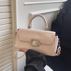Pale pink faux leather crossbody bag with a sparkling G-letter buckle and top handle