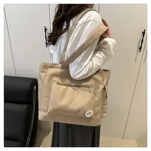 Detail of khaki nylon tote bag featuring spacious zippered pockets and decorative patch