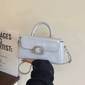 Close-up of light blue patent leather handbag with rhinestone G buckle and top handle