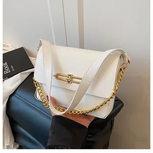 Detail of white leather shoulder bag with gold metal chain strap and sleek bar closure