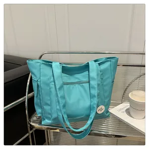 Detail of teal nylon tote bag with front zipper pocket and decorative lucky patch