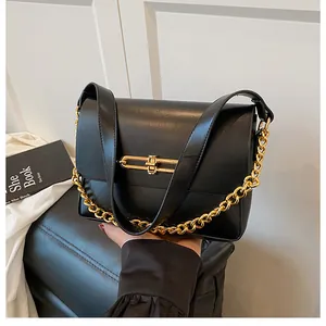 Detailed view of black textured leather handbag with gold metal clasp and chain strap