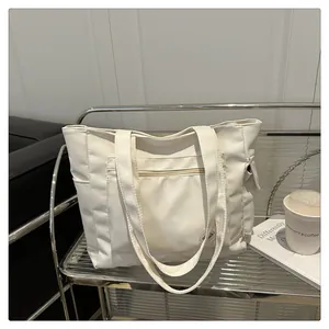 Detail shot of the white canvas tote bag with front pocket and side storage pockets
