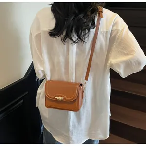 Detail shot of brown PU leather crossbody bag with golden cylindrical buckle and strap