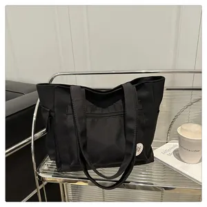 Detail of a black canvas tote bag featuring front zipper pocket and Good Luck patch