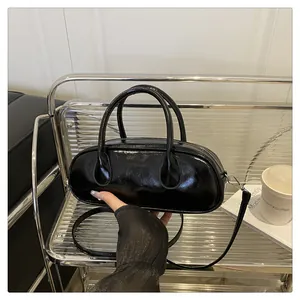 Details der glänzenden schwarzen ovalen Handtasche mit silbernen Elementen im Regal