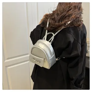Silver mini backpack featuring a metallic finish and delicate bow detail on model