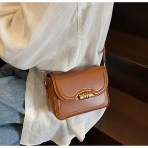 Close-up of caramel brown PU leather crossbody bag with elegant gold metal cylinder lock