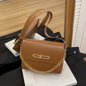 Brown leather handbag with gold chain strap and metallic buckle in a mirror reflection
