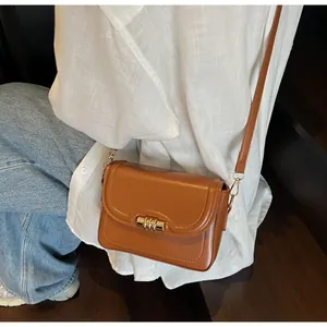 Brown leather crossbody bag with gold metal lock shown as a daily outfit detail