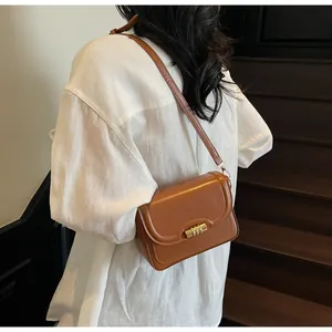 Detailed side view of caramel leather shoulder bag with gold metal clasp on a model
