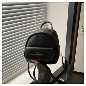 Detail shot of mini black PU leather backpack with bow accent and smooth zipper closure