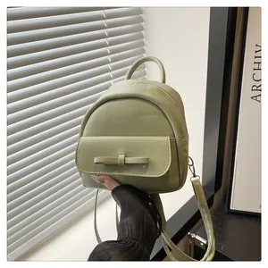 Detail of mint green mini backpack featuring leather texture and a bow design