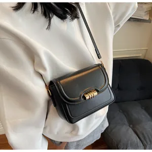 Detail of minimalist black PU crossbody bag with unique wavy flap and golden ring hardware