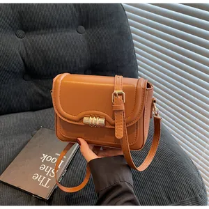 Detailed close-up of brown PU leather crossbody bag with golden twist lock and adjustable strap