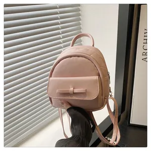 Detail of pink mini backpack with a delicate bow accent and premium leather texture