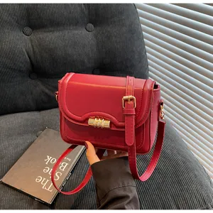 Detail of red vintage PU leather crossbody bag with golden clasp and adjustable strap