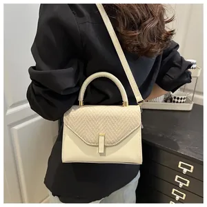 Detail of cream white leather handbag with beige woven texture and gold magnetic clasp
