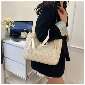 Détail de la texture tissée dense et des lanières en cuir blanc de ce sac cabas en paille