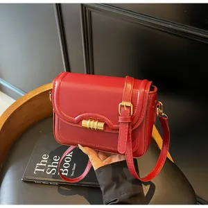 Detail view of red leather crossbody bag with premium gold hardware and flap closure