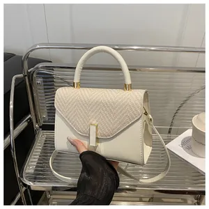Detail of white leather and beige woven fabric kelly bag with golden metal hardware