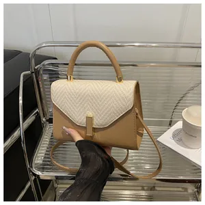 Close-up of khaki woven texture flap and smooth beige leather with gold metal clasp