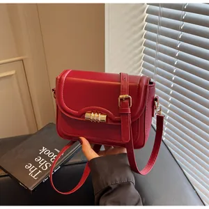 Detail view of dark red vintage faux leather crossbody bag with gold cylindrical lock