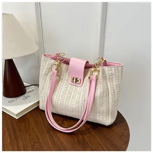 Détail d'un sac cabas en paille tissée avec rabat en cuir rose et fermoir doré rotatif
