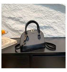 Detail of grey denim and black leather shell-shaped handbag with golden hardware