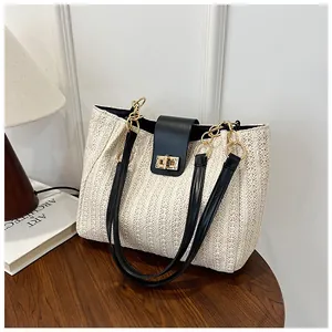 Détail d'un sac cabas tissé main avec fermoir en cuir noir et boucle tournante dorée