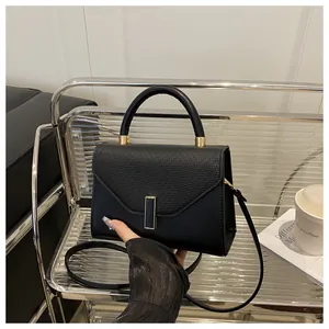 Detail of black leather handbag with lizard pattern flap and elegant metal clasp